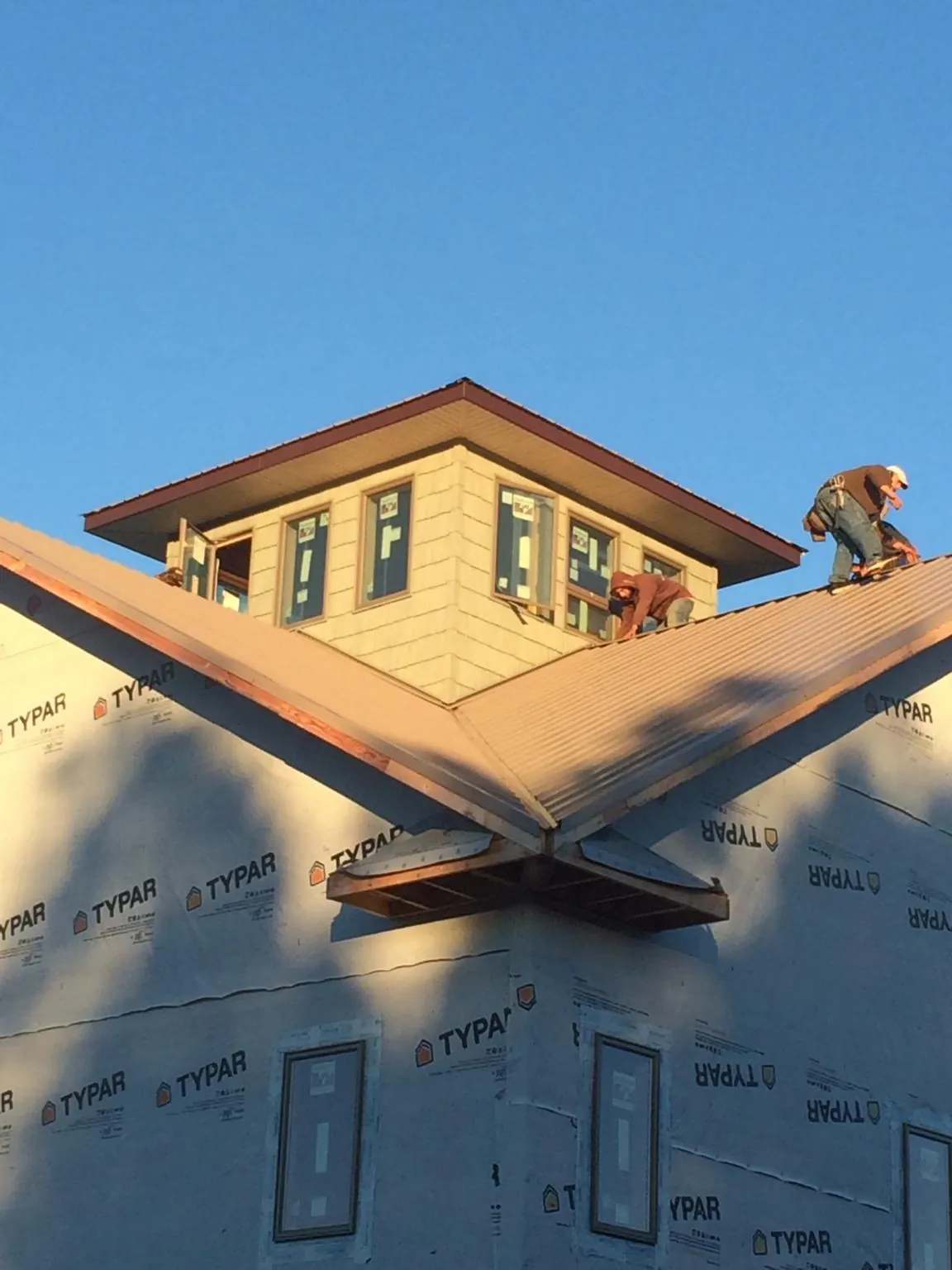 Roofers working around a rooftop cupola on a new metal roof at sunset — Roof Waterproofing in Arkadelphia by Roofing Brothers